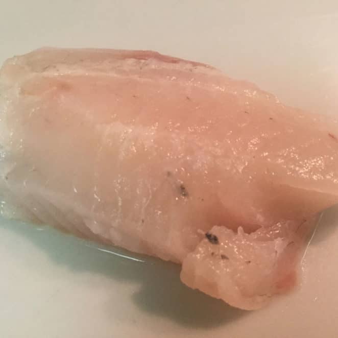 The black stuff on this tilapia filet is probably fish skin and with a trim it's OK to eat