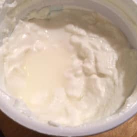 Yogurt with a puddle of liquid at the top. The liquid is whey and is entirely edible.