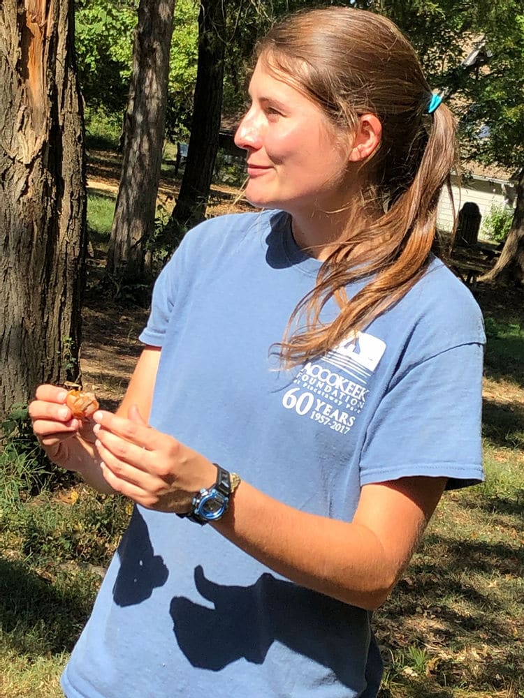 KC Carr holds a small persimmon in the National Food Forest