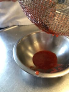 pressing strawberry juice out of strawberry tops